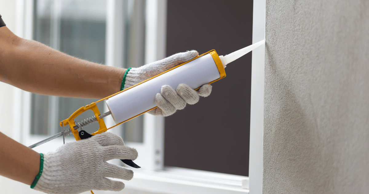 Person applying sealant with a caulking gun