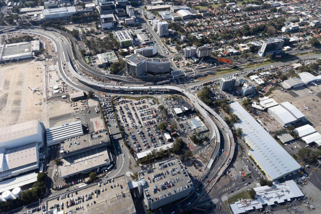 Aerial view of the completed Sydney Gateway Project showing new elevated roads, bridges and upgraded connections around Sydney Airport with traffic moving smoothly.