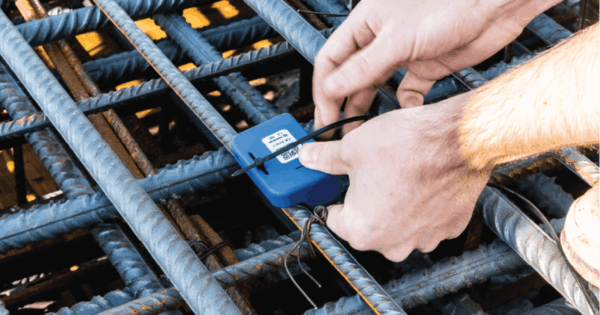 Worker installing Converge Signal concrete temperature sensor on rebar before pour