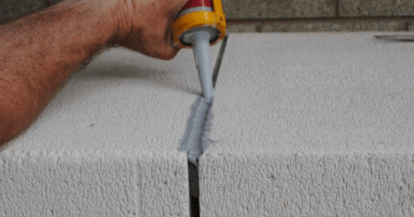 Applying MS polymer sealant to concrete block joint for smooth paintable finish.