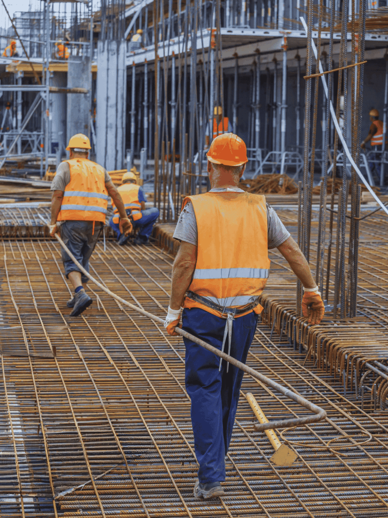 Workers installing steel reinforcement bars on a construction site for concrete reinforcement.