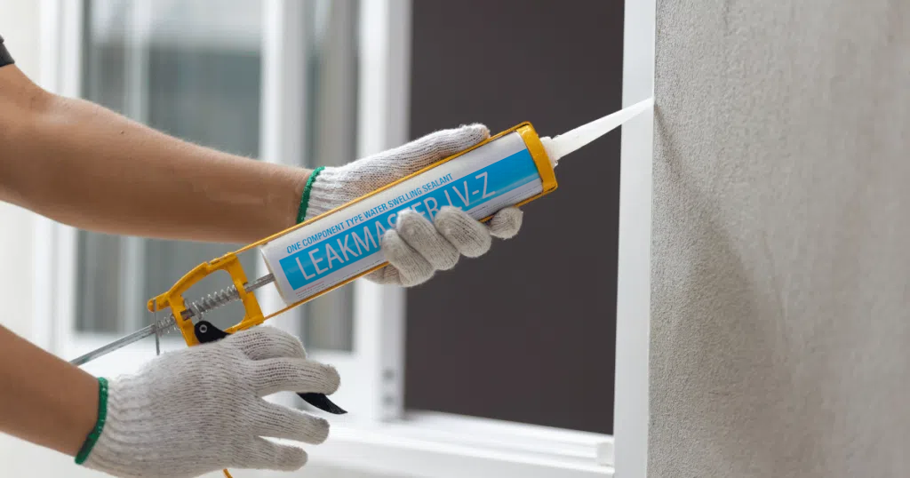 Person applying sealant with a caulking gun